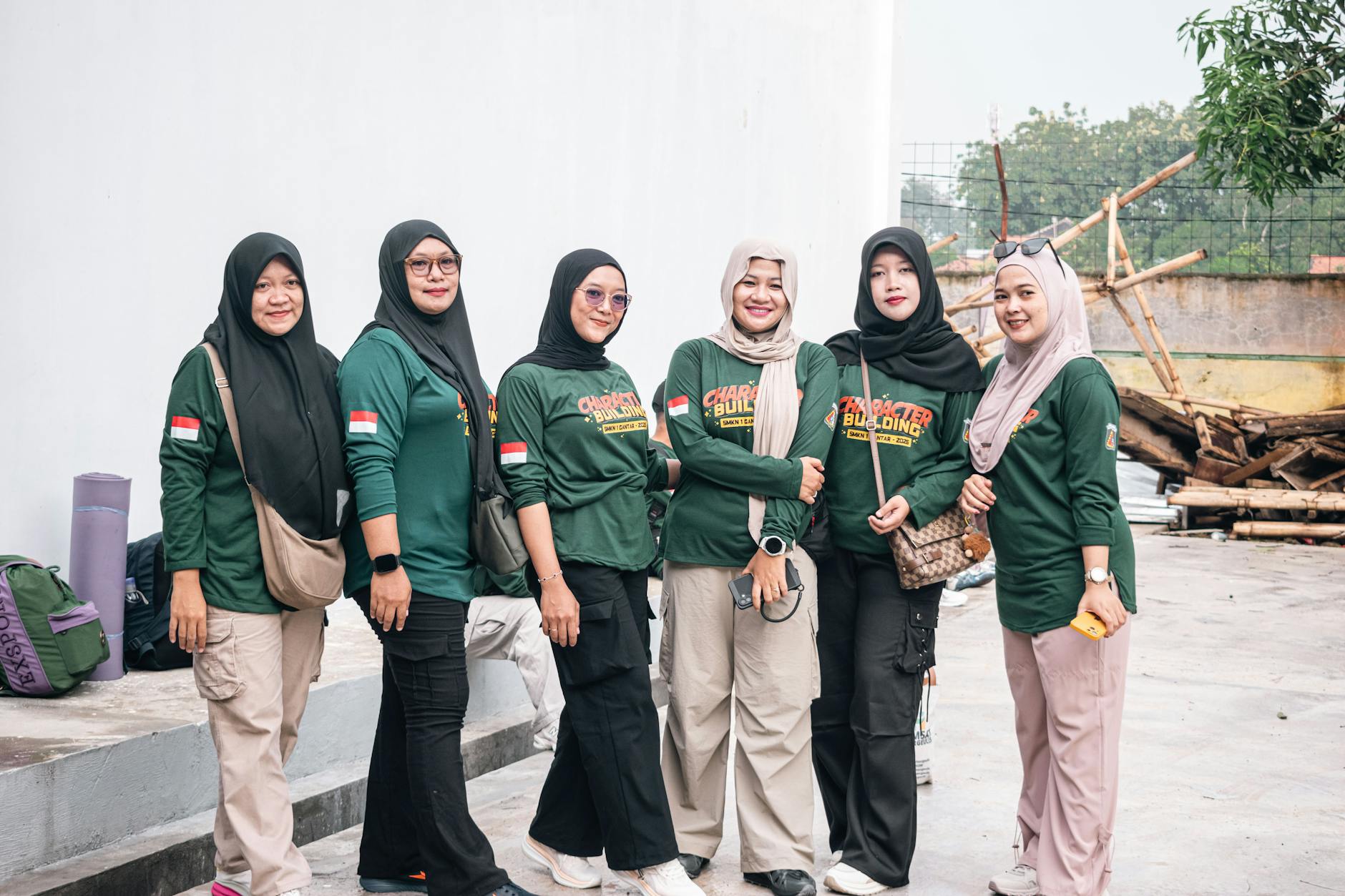 Seorang pramuka gagah berani sedang mengibarkan bendera di depan tenda perkemahan.